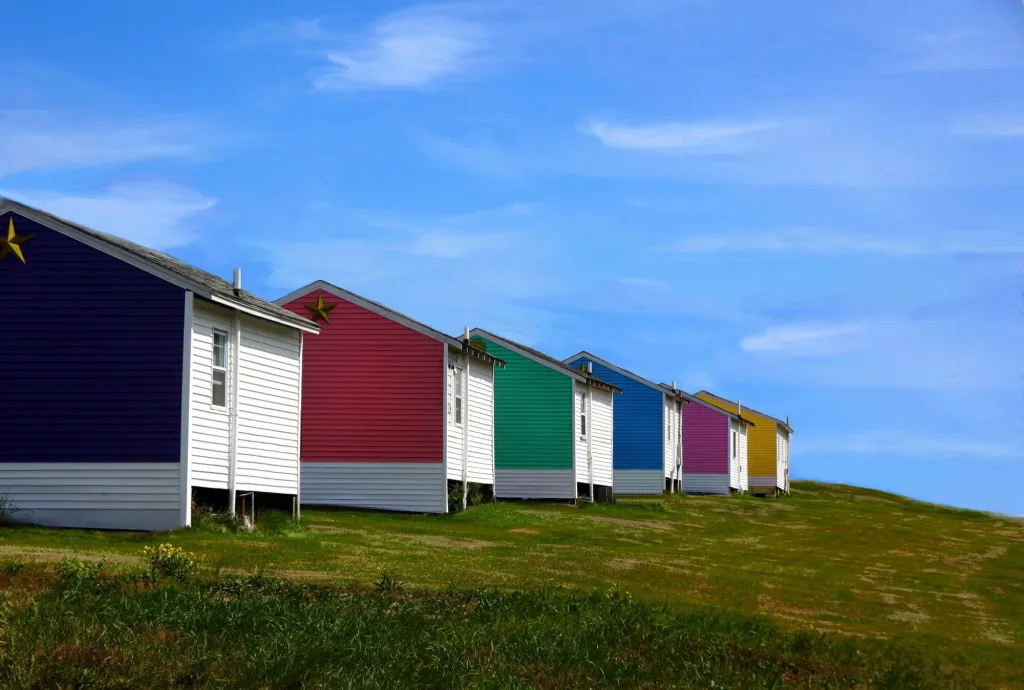 Row of beach huts painted in bright colours under a blue sky