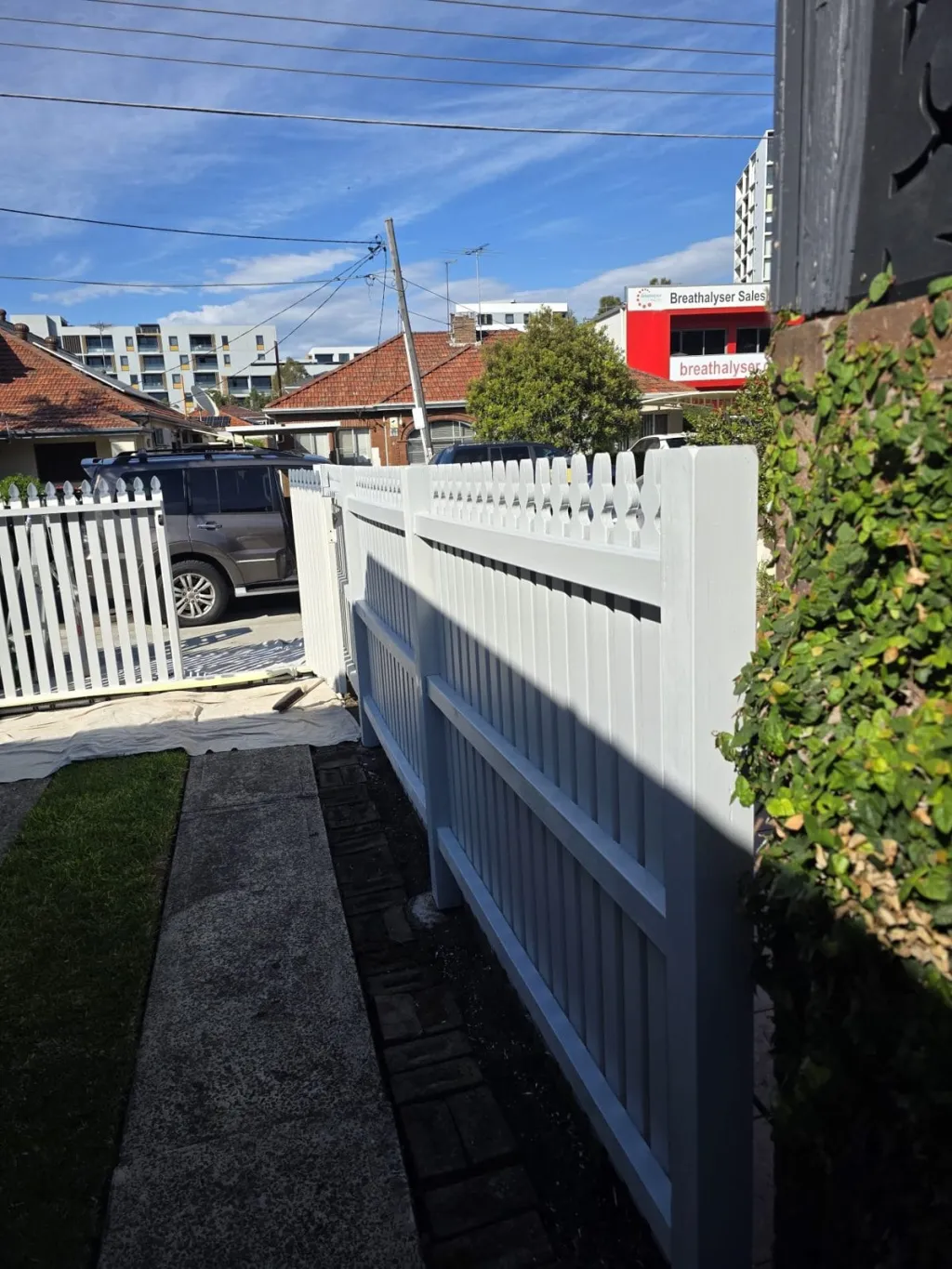 White picket fence repaint on a street of brick bungalows