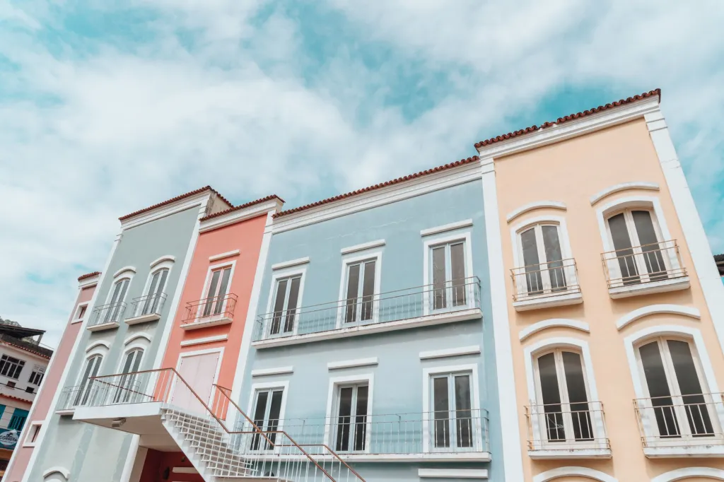 Pastel-painted building facades under a cloudy blue sky