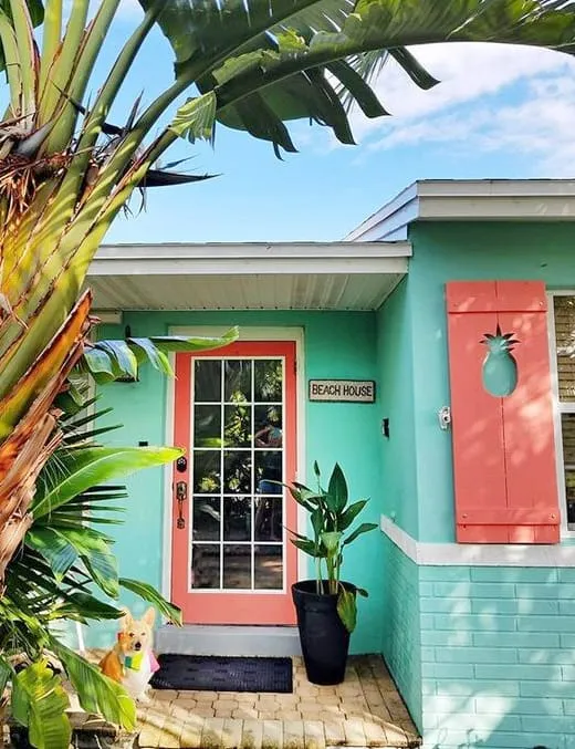 Beach house painted turquoise with a coral front door